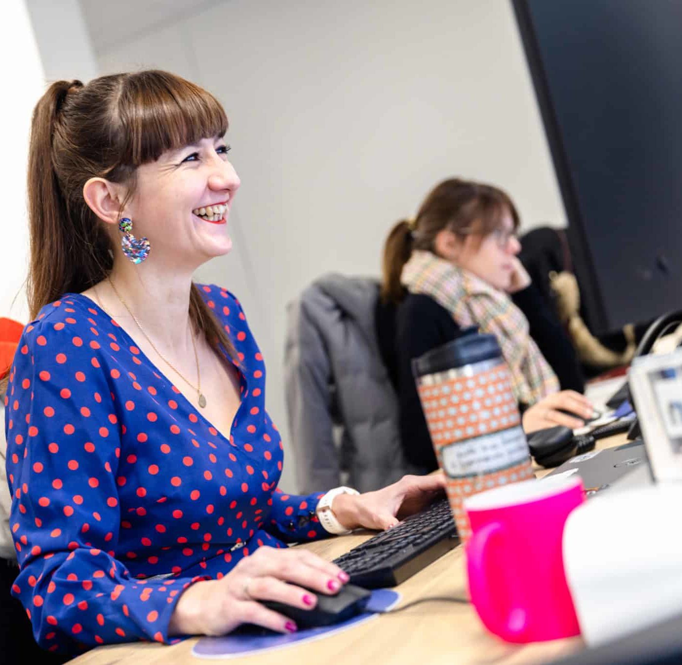 Portrait d'une collaboratrice souriante assise dans les bureaux de l'agence Winbound