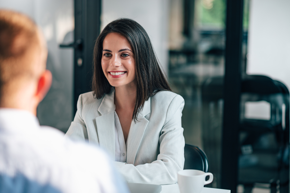 Une femme échange avec un client de dos dans un bureau